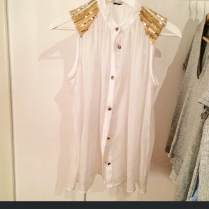  - Trnsparant partytopp med guldknappar och paljettaxlar. 