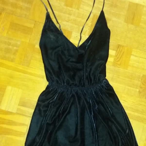  - Klänning i mörkblå sammet. Stretchig resår i midjan och öppen rygg. Skickas mot frakt.