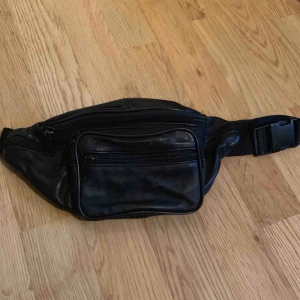  - Svart magväska i jättebra skick med fem små fack fram och ett bak! Praktisk och snygg. Kan justeras mindre och större. Frakt tillkommer 💫