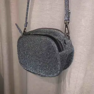 Silvrig/glittrig väska från Pull & Bear som lyfter vilken outfit som helst! Justerbar axelrem.   Betalas med swish. Kan mötas upp i Halmstad eller skicka mot frakt som betalas av köparen. 