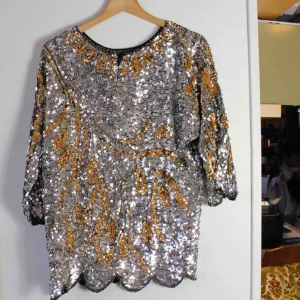  - Väldigt fint vintageplagg i 100% silke, silvriga och guldiga paljetter. Jag är en strl S och på mig är den oversized så skulle säga att den snarare är en L i storlek. Spårbar frakt 63kr.