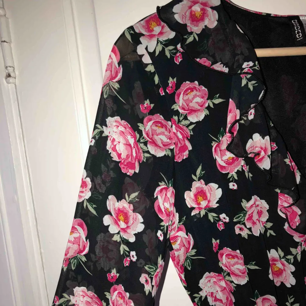 Super söt klänning med rosa blommor på💗💗 Den är i ett liknade ”mesh” material💗 är v-ringad vid bröstet och har volanger som detaljer💗💗. Klänningar.