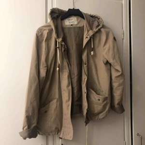  - Vindtätt tun jacka som passar perfekt för våren och hösten.