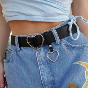  - Svart skärp i faux skinn/läder med hjärtformat spänne! Helt nytt och oanvänt, mäter ca 100cm med spännet. Går att ta bort det lilla hjärtat. Frakt ingår i priset!