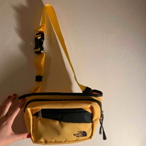  - The North Face fannypack, stl M. Perfekt att få plats med telefon, nycklar och lite annat smått! Totalt 3 stycken fack. Fin gul färg 🌻🌼🌞   Aldrig använd! 