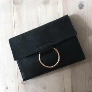  - Svart liten kuvertväska/börs med guldring Tryckknapp (dold) och avtagbar axelrem i svart med gulddetaljer  Läderimitation, köpt i Spanien  13cm hög och 19cm bred