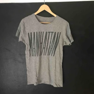  - Grå t-shirt från Lager 157. Trycket säger ”MANHATTAN”. 