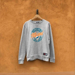  - Miami Dolphins NFL crewneck i trevligt använt skick. Kan hämtas i Uppsala eller skickas mot fraktkostnad. Storlek L. Något liten i modellen.