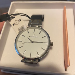 Klocka / armbandsur  - Armbandsur från Mockberg ( Astrid ). Helt oanvänd med plastskyddet kvar. Nypris 1299 kr. 