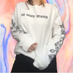 White sweater with ‘no more drama’ written over the chest, rose pattern down the sleeves. 