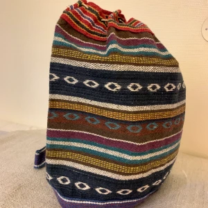 Ryggsäck  - Stor randig ryggsäck köpt på loppis. Nåt slags presenning/plast invändigt. Stängs genom snöre som man knyter. Rymmer mycket! Perfekt som weekend bag eller liknande.