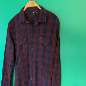 Skjorta från Lee av flanelltyp  - Mjuk skjorta från Lee stl XL slim fit med tryckknappar i lila och mörkblått. 