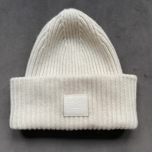 ACNE MÖSSA VIT - Säljer min fina acne mössa eftersom jag inte använder den längre. Använd ganska mycket förra vintern men annars inte alls. Buda från 400kr. Kunden står för frakten😊😊Högsta bud just nu 700kr