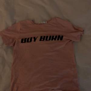 T-shirt från na-kd med text: boy burn, rosa i färgen, blir enkelt skrynklig säljer den därför för ett billigt pris. Säljer den för att den är för liten 