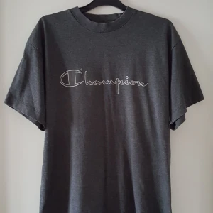  - Mörkgrå vintage Champion t-shirt i storlek M. Finns i Örebro men kan skickas om köparen står för fraktkostnaden på 36kr.