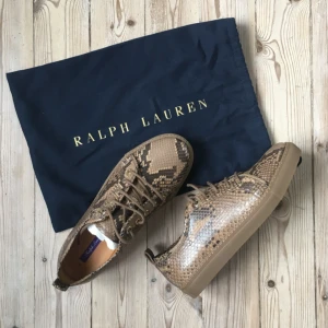  - Helt nya Ralph Lauren sneakers från deras purple label. Skinn med snake-imitation och tjock gummisula. Storlek 38 (jag skulle säga en stor 38). Klassiker!   Kan mötas upp i Sthlm eller skicka - köparen betalar frakt :)