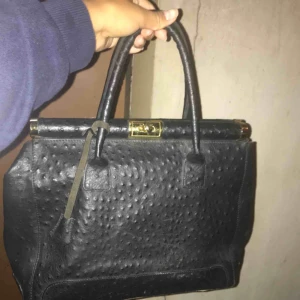  - Svart väska i äkta skinn av ett italienskt märke ”Pelle di Lj”. Gulddetaljer.