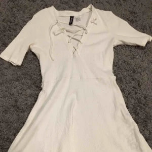  - Vit klänning med korsning över brösten, räfflad i materialet.