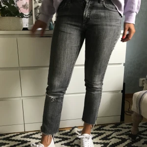 Gråa jeans - Gråa skitsnygga jeans från ginatricot med hål i ena knäet och slitningar längst ner på byxbenen. Köparen står för frakt som är cirka 80kr eller mötes upp i Borås.