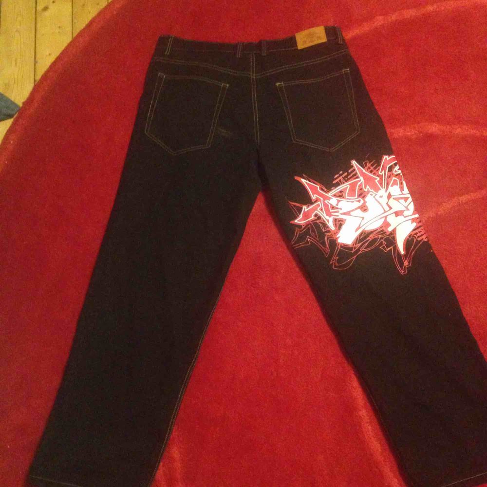 Jätte coola townz jeans som är svarta med röd/vit grafittin målning runt vänstra benet. . Jeans & Byxor.