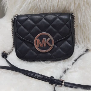  - liten Michael kors väska  i svart skinn  perfekt kvällsväska eller när man bara behöver det nödvändigaste med sig.  väskan har en lång axelrem så den går att använda crossbody. 2 fack i väskan och 1 fack på utsidan bak. Givetvis är den äkta ,  köpt på ragladys hemsida för ett år sedan för 1899kr . Använd endast ett fåtal ggr så den är i super skick! Mitt pris 800kr 