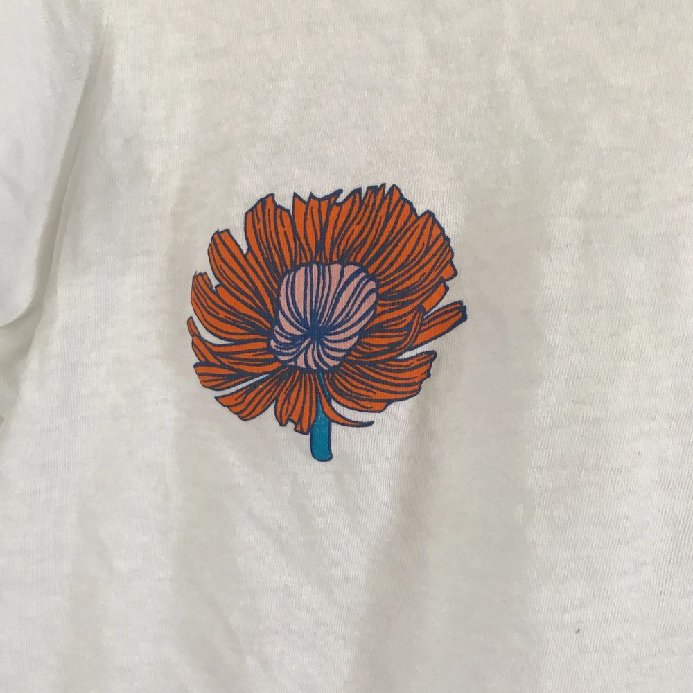 Vit T-shirt Med blommor på brösten. Normal i storleken . T-shirts.