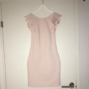 - Snygg och vacker rosa klänning med volanger. Snygg figursydd passform. Perfekt längd, inte för kort och inte för lång. Djup i ryggen vilket är väldigt snyggt. Aldrig använd.