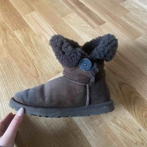 UGG’s Bailey Button - Säljer ett par Uggs i modellen ”Bailey Burton”. Väl använda, relativt slitna men fortfarande fina. Ett pyttelitet hål på ena skon, se andra bilden. 