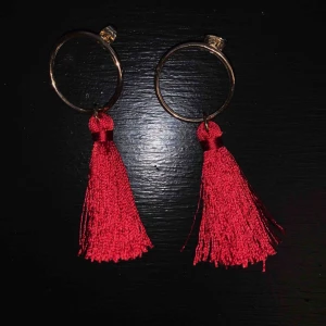  - Fina guldiga örhängen med röda ”tofsar”. Använda en gång, fler bilder kan skickas och frakt ingår ej. 