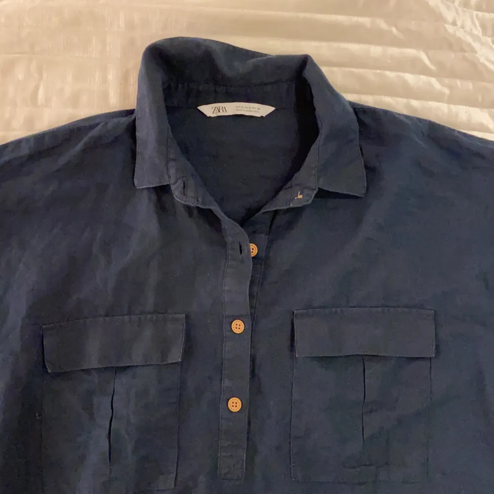 Mörkblå skjorta med bruna knappar och bröstfickor i linnetyg. Köpt från Zara i strl S. Använd 1 gång. . Skjortor.