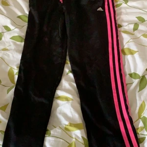 Adidas Byxor strl 158/164 - Byxorna är svarta med rosa sträck på sidorna, gammal modell, ganska liten i storleken