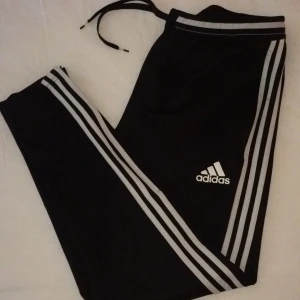 adidas träningsbyxor - träningsbyxor från adidas med drajkedjor vid benen, knytning i midjan, 2 framfickor med dragkedja. Nästan som nya, då det är små knottar på byxorna men annars som nya. Köpta för 399kr, mitt pris 175kr exklusive frakt. 