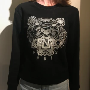 Kenzo tröja! - Svart collegetröja med silvrigt kenzotryck! Storlek L men är väldigt liten i storleken. Använd ett fåtal gånger!