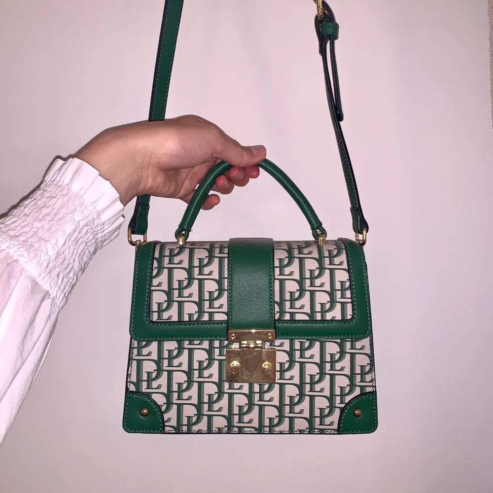 Söt väska i grönt mönster köpt i Paris på Tom&Eva! Väskan har mycket detaljer, en grön ficka på baksidan och många fack inuti. Kan skicka fler detaljbilder i chatten!🥰. Väskor.