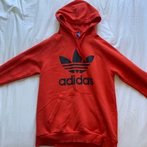 Röd hoodie från Adidas - Mysig röd oversized hoodie, använd men är i bra skick utan fläckar eller hål. Kommer ursprungligen från herravdelningen men passar fint på mig som vanligtvis är en S-M! Säljer för att jag har för mycket hoodies.💞💞
