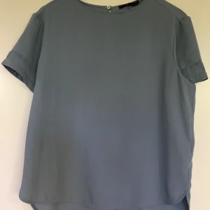 Blus/ topp - Topp i ljusblå mot grå ton från Åhléns. Fin detalj med mesh på armen. 