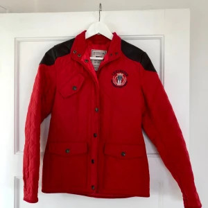  - Klassisk röd jacka från Lexington med bruna läderdetaljer på axlarna. Storlek S. Sparsamt använd.  Skickar med posten spårbart eller möts upp i Stockholm.