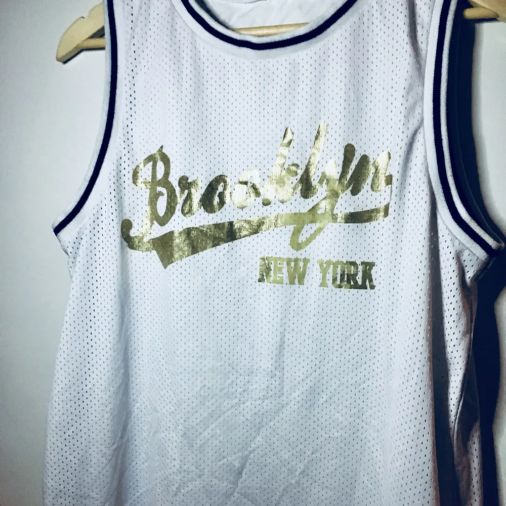 Kort klänning /långt basket linne modell med texten Brooklyn new york i guld. Köpt på Asos och använd fåtal ggr. (Frakt tillkommer om du ej kan hämta på plats). Klänningar.