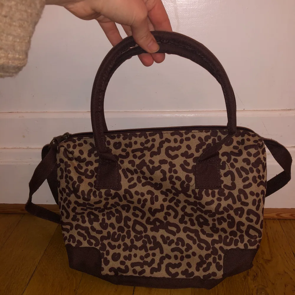 Supersöt handväska med leopardmönster. Liten väska med handtag och ett justerbart axelband. . Väskor.