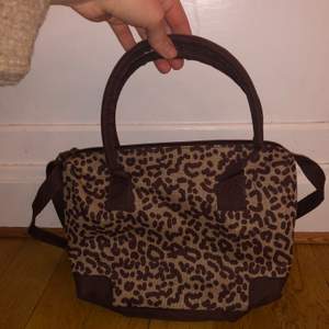 Supersöt handväska med leopardmönster. Liten väska med handtag och ett justerbart axelband. 