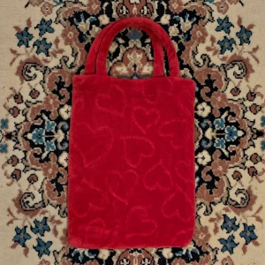 Röd vintage fluffig väska med hjärtan - Äkta vintage röd fluffig väska i fett coolt tyg med “imprinted” hjärtan 🧶 Lätt färg att jobba med som gör att du antingen kan matcha den med andra röda element i din outfit eller ha den som en statement piece till en neutralare outfit!-   Alla priser är inkl. frakt och alla plagg tvättas innan de skickas iväg