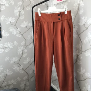 Raka byxor - Paper bag byxa i brunt/orange. Fin passform med mjukt material. Strl 34 från Mint & berry