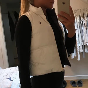 Vit Ralph Lauren väst - Jätteskön vit raffe väst med lila inuti, man kan ha den på båda hållen. Barnstorlek 12/14 men passar mig med Xs/S. Säljer pga att jag köpt en vit moncler väst istället. Perfekt till hösten/vintern. Högsta budet just nu är 500kr + frakt!