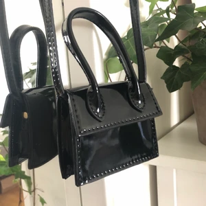 Supersöt mini bag - Superfin svart minibag, lackfärgad/glansig. Obs den är liten, ca 10cm lång. Den har ett litet hantag men ett längre band som går att ha över axeln osv. Fint skick, aldrig använd! 
