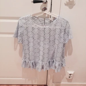  - Ljusblå topp från River Island. I spets med inbyggt linne under i samma färg. Dragkedja i ryggen och volang nedtill. Använd en gång, i mycket fint skick. Kan skicka fler bilder vid intresse! 