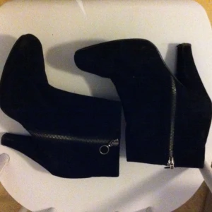 Svart mockaimitation, rosa innertyg och dragkedja på utsidan. - Svart mockaimitation, rosa innertyg och dragkedja på utsidan.