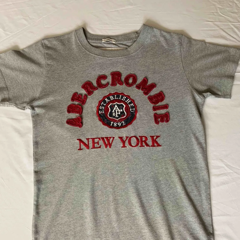 •Grå t-shirt från Abercrombie and Fitch •Rött motiv •Mycket bra skick, sparsamt använd  •Stor i storleken  . T-shirts.