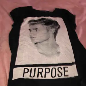 En svart T-shirt med Justin Bieber på, strl s men passar xs också då man kan knyta up den eller peta in i byxorna. Köpt på new yorker använd cirka 10 gånger kanske. Väldigt skön T-shirt att sova i eller ha till ett par snygga byxor