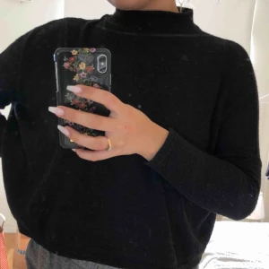  - Svart, varm tröja. Passar bra till hösten men även till sena sommarkvällar! Kanske över en klänning eller till kjol! Smal i underarmen och större i överarmen och ganska ”flowig” men ändå kort. 