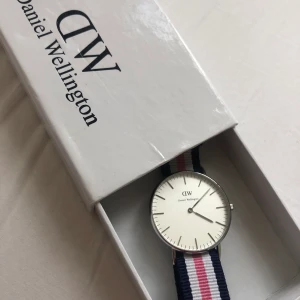 Daniel Wellington klocka - Superfin klocka från Daniel Wellington med rosa/vitt/blått band. Behöver nytt batteri, annars som ny. Nypris 1400